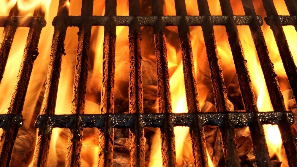 Photo of a grill near the fire, heating it to make meat for the grill.